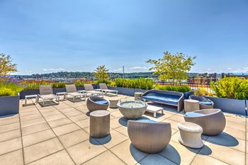 a roof terrace with chairs and tables overlooking a city at Wilcox, Seattle, 98107